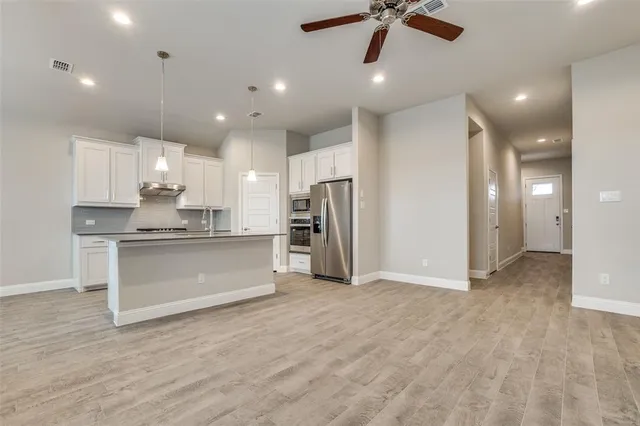 a view of an empty room with kitchen appliances and a window