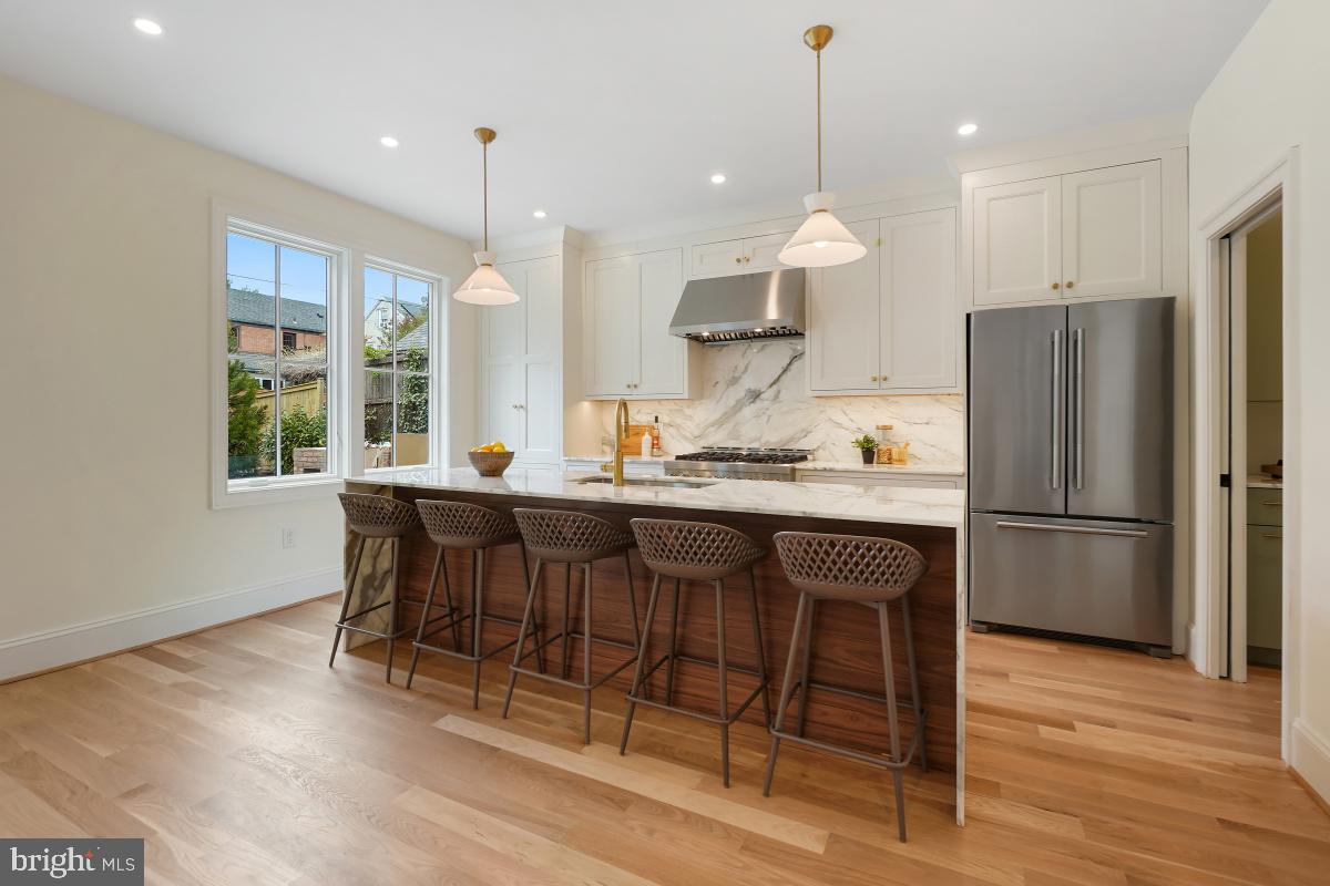 4339 Windom Place Northwest Washington, DC 20016 - Photo 14 of 45 a kitchen with stainless steel appliances granite countertop a refrigerator a stove a sink dishwasher a dining table and chairs with wooden floor