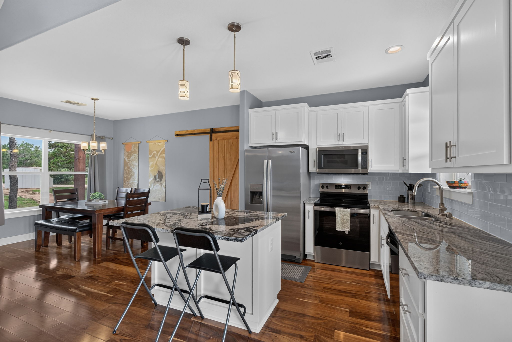 207 Deer Ridge Drive Burnet, TX 78611 - Photo 21 of 36 Granite counters and stainless appliances define this modern kitchen with rich hardwood flooring.