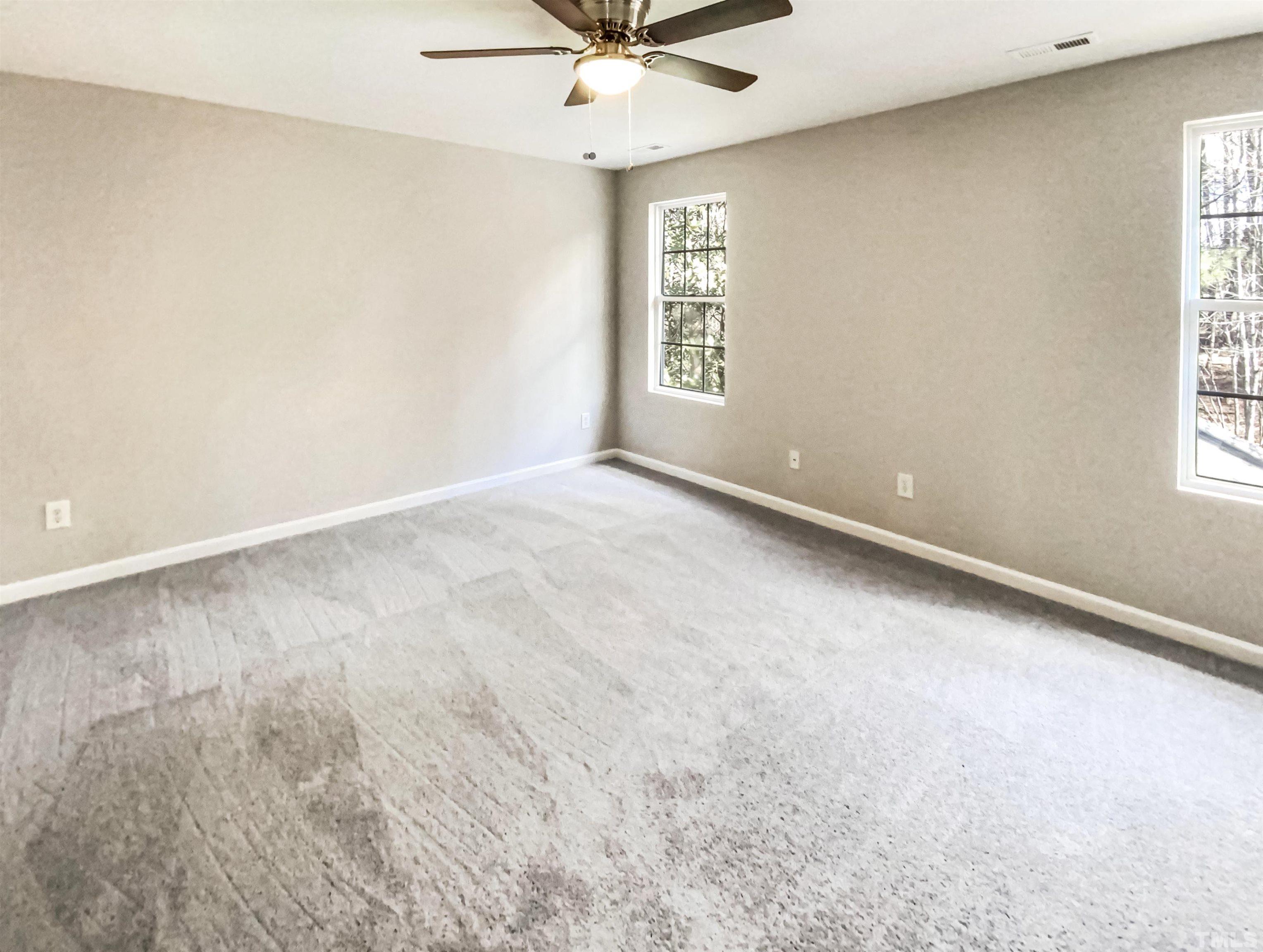 203 Caley Road Apex, NC 27502 - Photo 6 of 19 an empty room with windows and ceiling fan