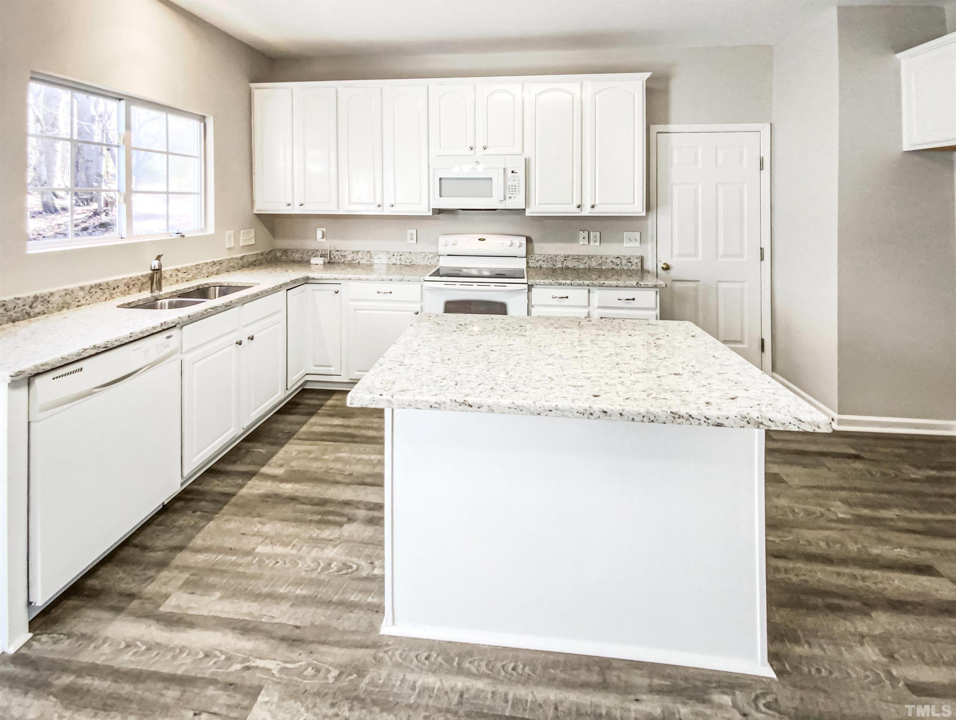 203 Caley Road Apex, NC 27502 - Photo 8 of 19 a kitchen with kitchen island a sink a stove a refrigerator and white cabinets