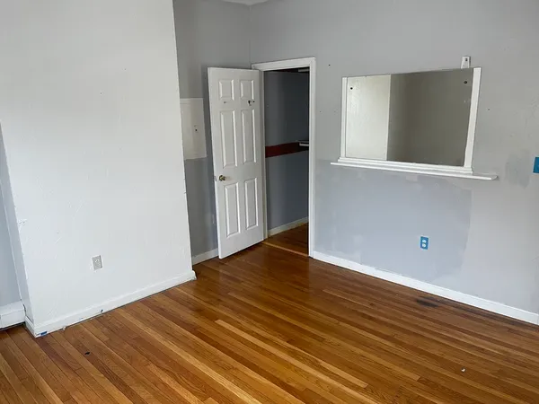 a view of an empty room with wooden floor and a window