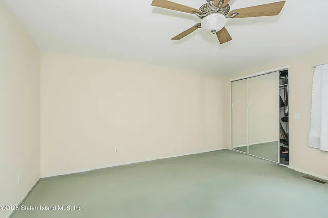 an empty room with a ceiling fan and a window