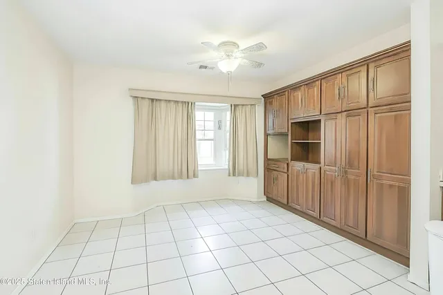 a view of an empty room with window and chandelier fan