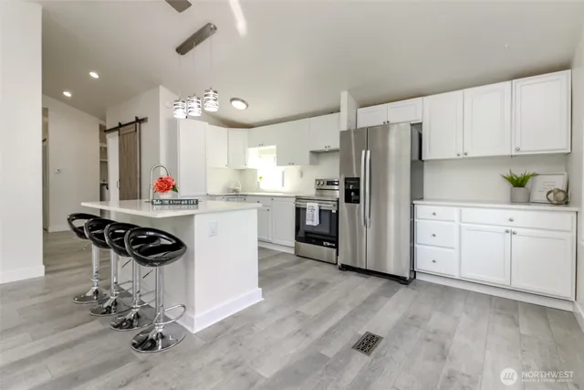 a kitchen with a refrigerator a stove top oven a sink dishwasher and white cabinets with wooden floor