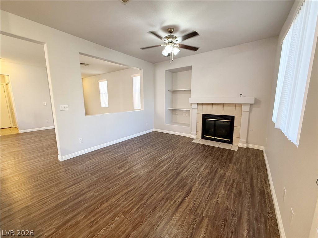 2185 Polynesia Circle Henderson, NV 89074 - Photo 9 of 37 A welcoming living room features a built-in fireplace, warm wood flooring, and a ceiling fan.