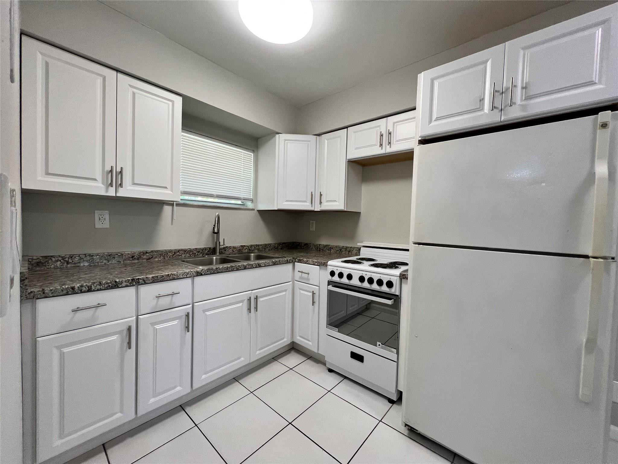 121 Southwest 15th Street, Unit C Pompano Beach, FL 33060 - Photo 1 of 13 a kitchen with granite countertop white cabinets and stainless steel appliances
