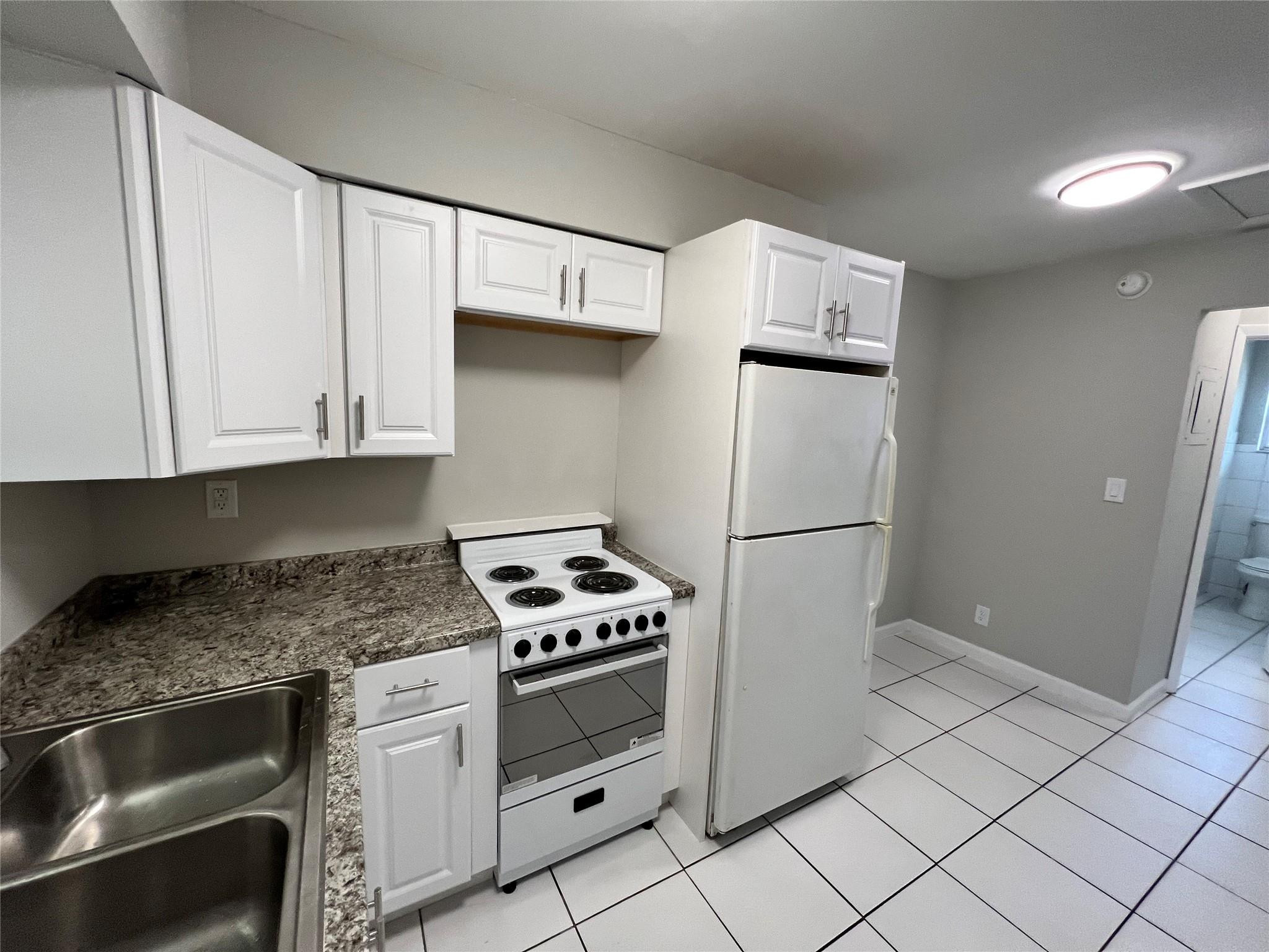 121 Southwest 15th Street, Unit C Pompano Beach, FL 33060 - Photo 2 of 13 a kitchen with white cabinets and white appliances
