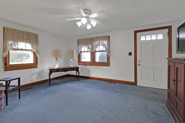 a view of an empty room with window and hardwood floor