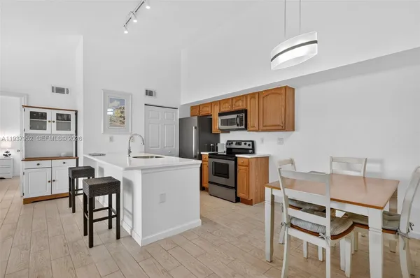 a kitchen with a refrigerator a stove top oven a sink dishwasher and white cabinets with wooden floor