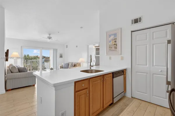 a living room with stainless steel appliances granite countertop a sink and dishwasher with wooden floor