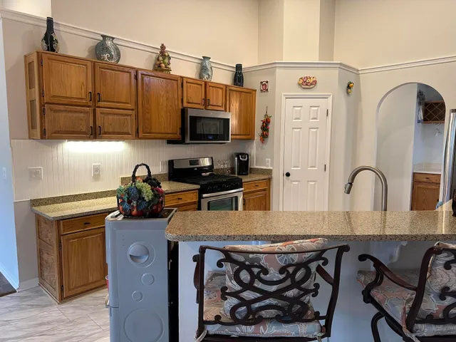 a kitchen with stainless steel appliances granite countertop a sink a stove and a wooden floors