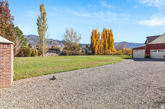 390 North 100 West Monroe, UT 84754 - Photo 29 of 167 View of green lawn with a mountain view, a garage, gravel driveway, and an outbuilding