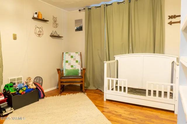 a view of a hallway with wooden floor and a bathroom