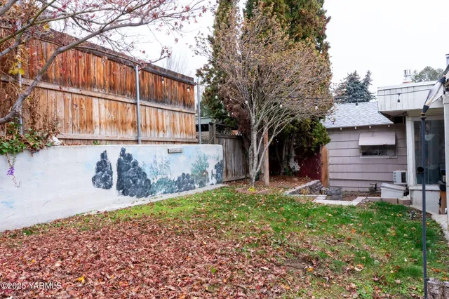 a view of small white house with a small yard and wooden fence
