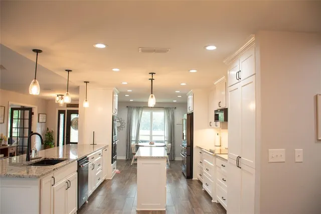 a large kitchen with granite countertop a large counter top appliances and cabinets