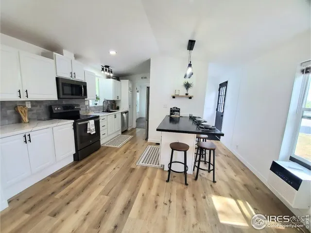 a kitchen with stainless steel appliances a stove top oven a sink dishwasher and a refrigerator with wooden floor