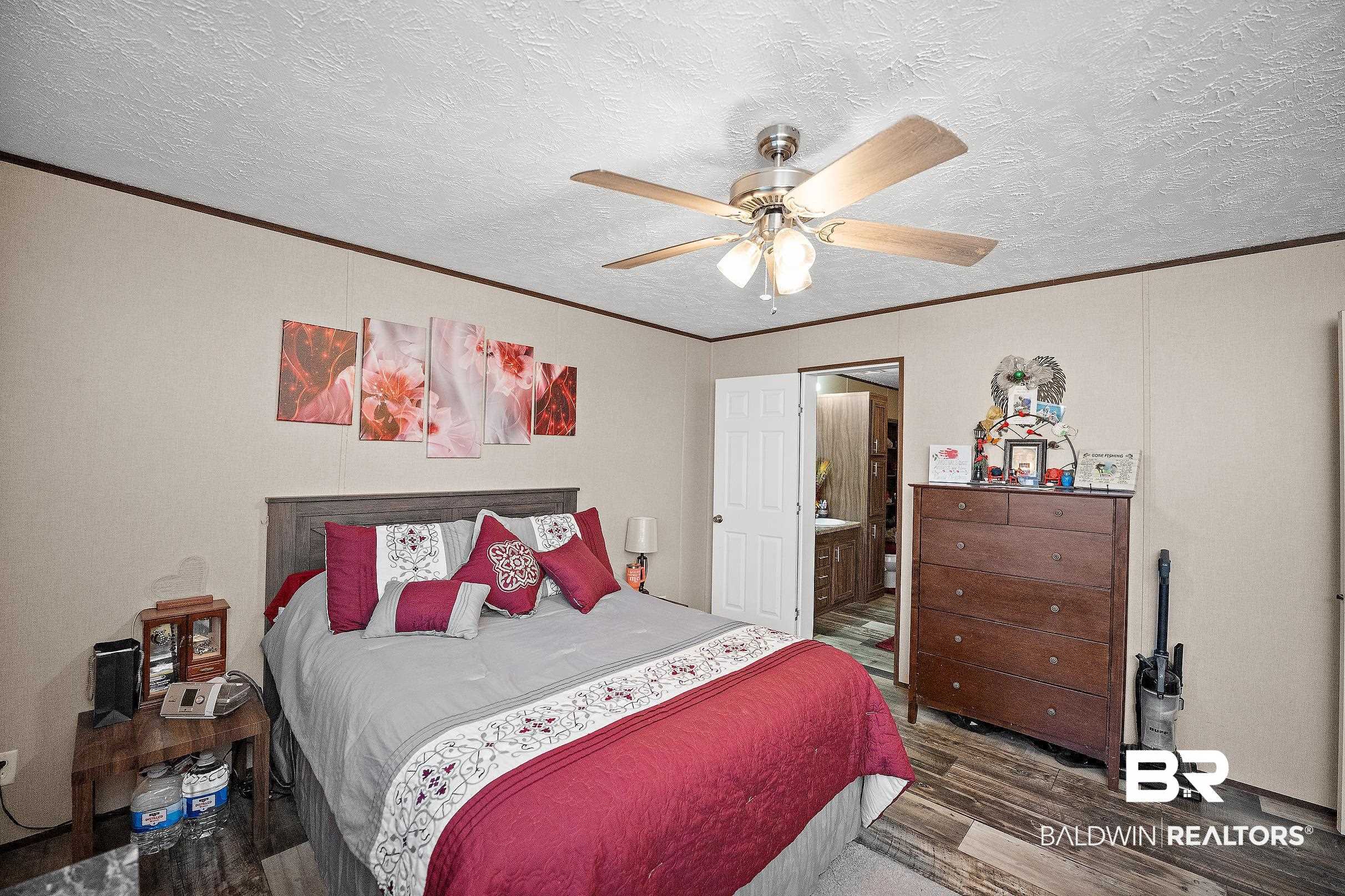 8630 Allison Lane Wilmer, AL 36587 - Photo 15 of 31 Bedroom featuring wood finished floors, ornamental molding, a textured ceiling, a ceiling fan, and ensuite bath