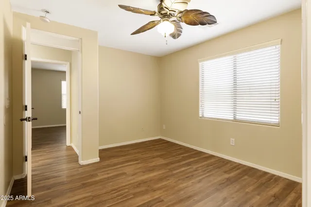 an empty room with wooden floor fan and windows