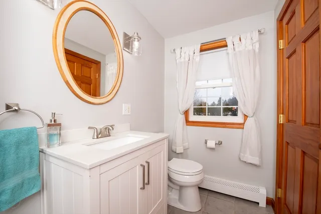 a bathroom with a toilet a sink a mirror and a window