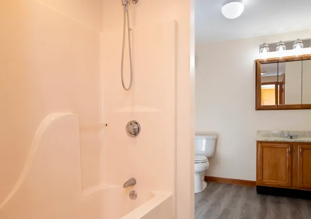 a bathroom with a granite countertop sink a toilet and shower