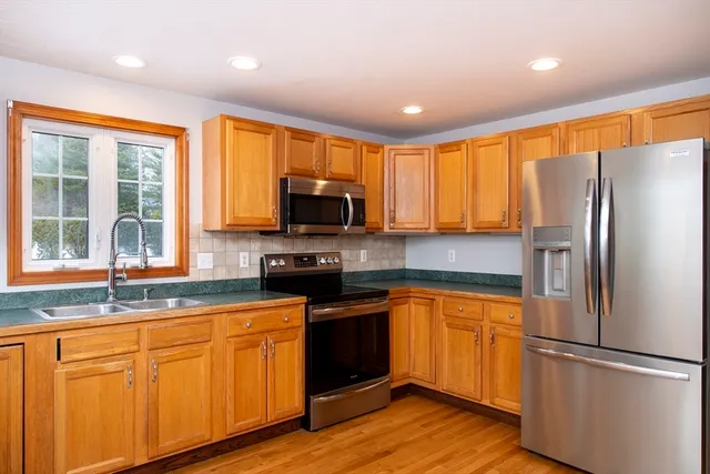 a kitchen with granite countertop stainless steel appliances a refrigerator cabinets and wooden floor