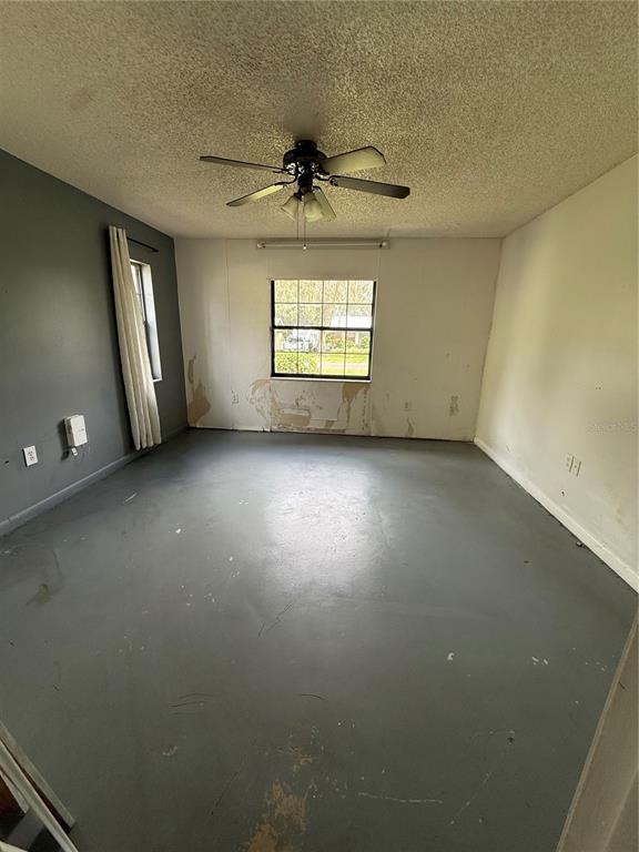 40907 West 3rd Avenue Umatilla, FL 32784 - Photo 6 of 13 an empty room with a chandelier fan and windows