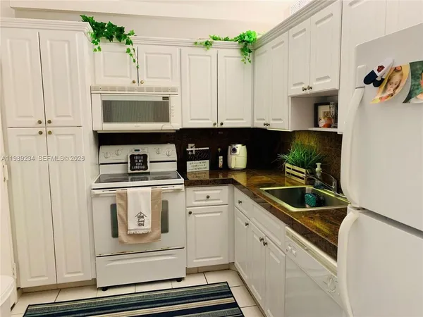 a kitchen with white cabinets and white appliances