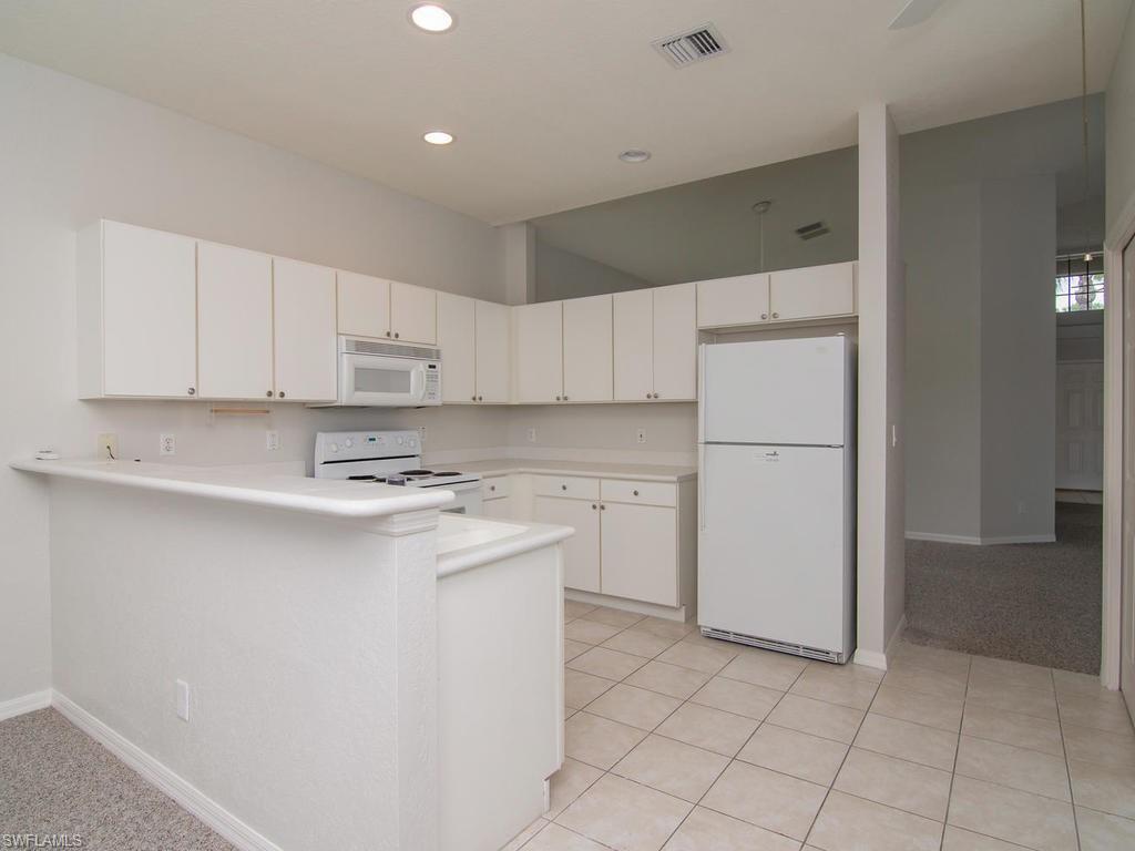 718 Crossfield Circle Naples, FL 34104 - Photo 5 of 17 a kitchen with a sink a refrigerator and cabinets