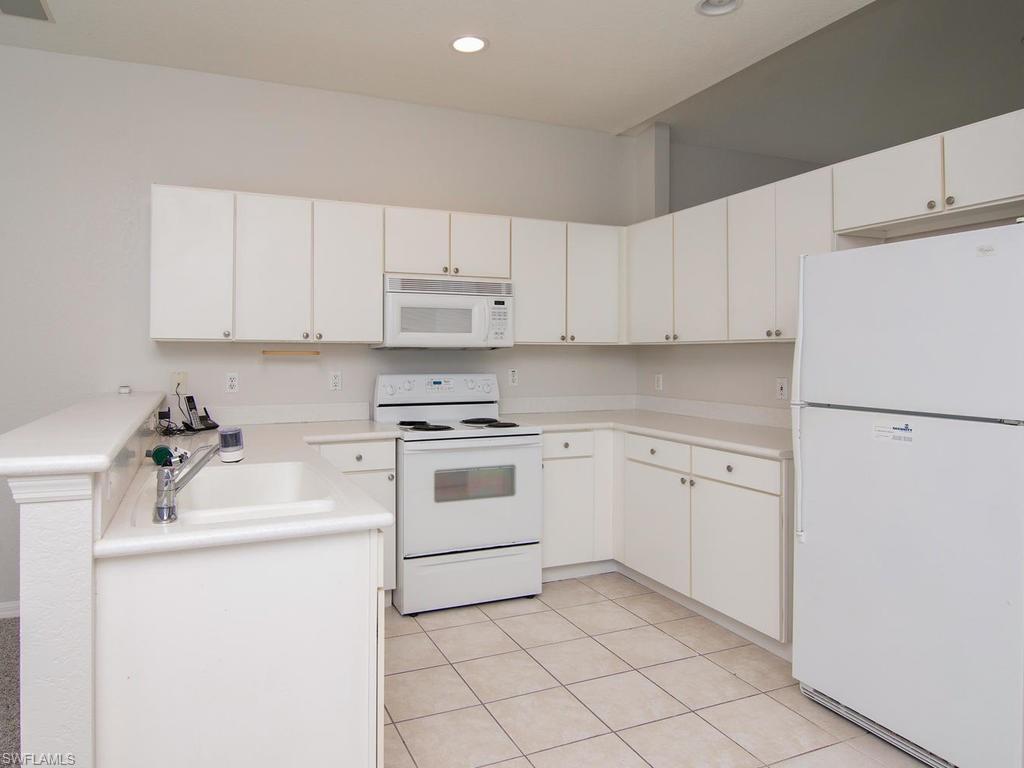718 Crossfield Circle Naples, FL 34104 - Photo 6 of 17 a kitchen with a white cabinets and white appliances