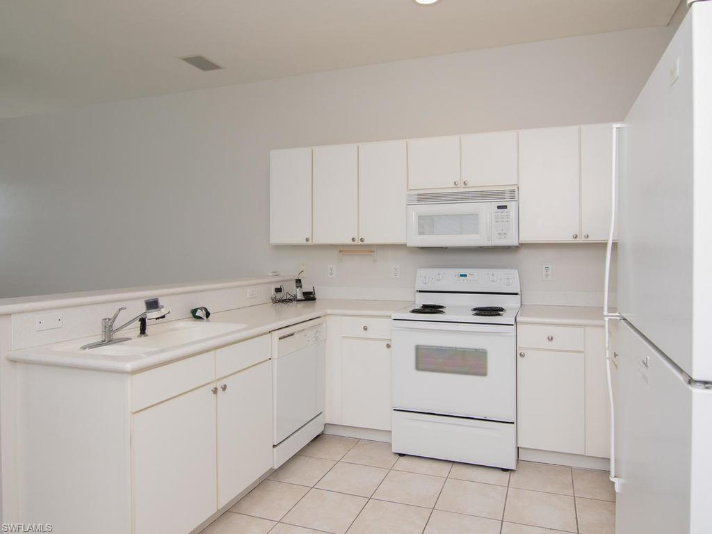 718 Crossfield Circle Naples, FL 34104 - Photo 7 of 17 a kitchen with cabinets appliances a sink and a stove top oven