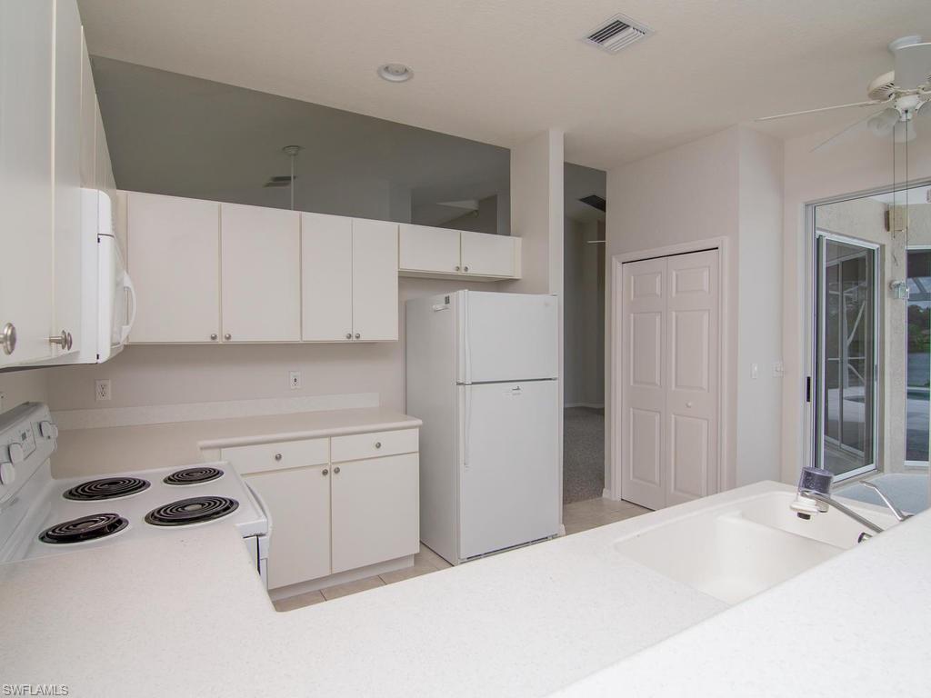 718 Crossfield Circle Naples, FL 34104 - Photo 8 of 17 a kitchen with a sink and refrigerator