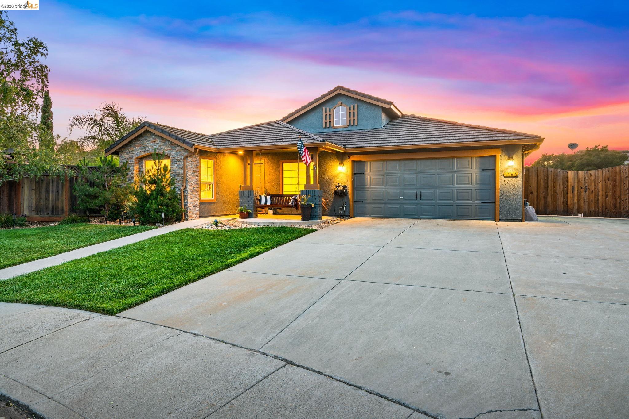 1186 El Rio Court Livermore, CA 94551 - Photo 58 of 60 Exterior featuring a stone facade, a covered front porch, a two-car garage, mature landscaping, and a concrete driveway