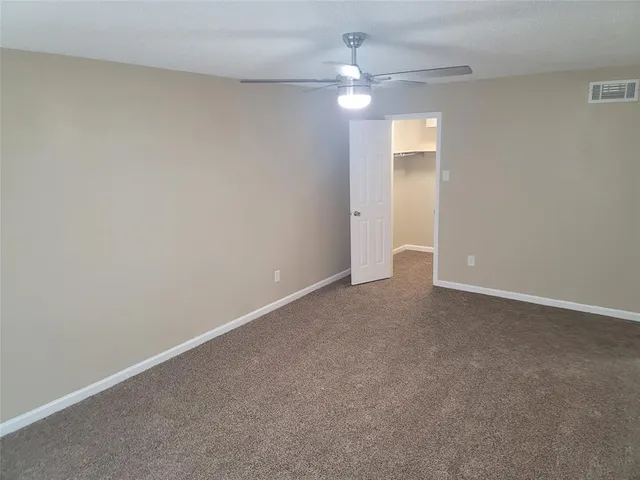 an empty room with a chandelier fan and a ceiling fan