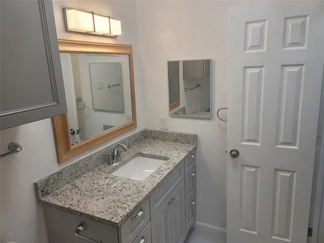 a bathroom with a granite countertop sink and a mirror