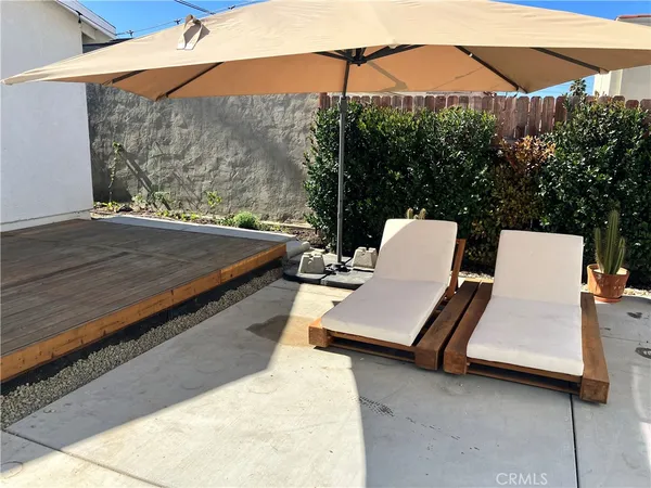 a backyard of a house with table and chairs under an umbrella