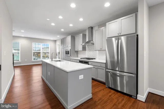 a kitchen with a refrigerator a sink and dishwasher with wooden floor