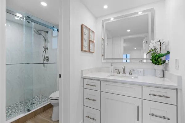 a bathroom with a granite countertop sink a toilet and shower