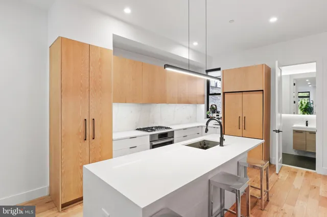 a kitchen with a stove a sink a kitchen island with chairs and wooden cabinets