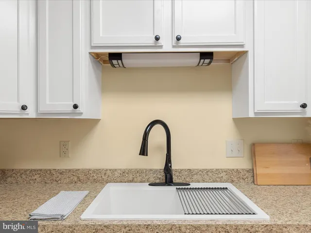 a close view of a sink a faucet and a stove in front of a door