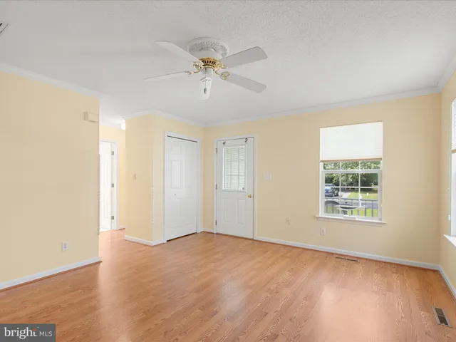 a view of an empty room with a window and wooden floor