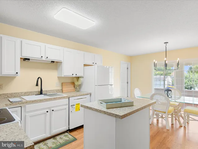 a kitchen with a sink a stove a refrigerator and white cabinets with wooden floor