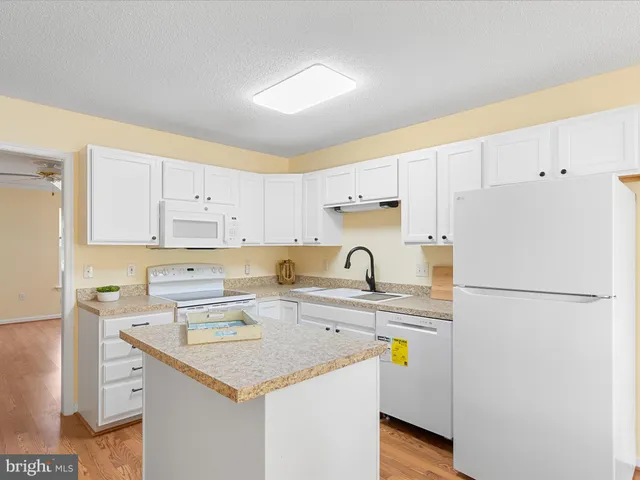 a kitchen with a sink a refrigerator and white cabinets