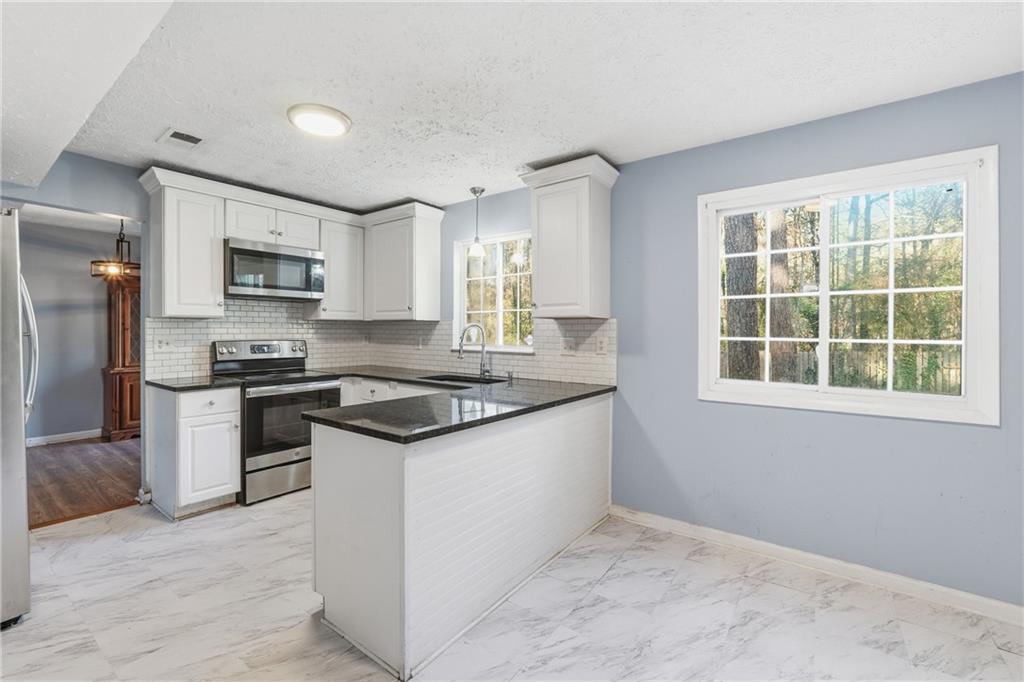 4828 Oak Path Stone Mountain, GA 30088 - Photo 11 of 40 a kitchen with stainless steel appliances granite countertop a stove a sink and a refrigerator