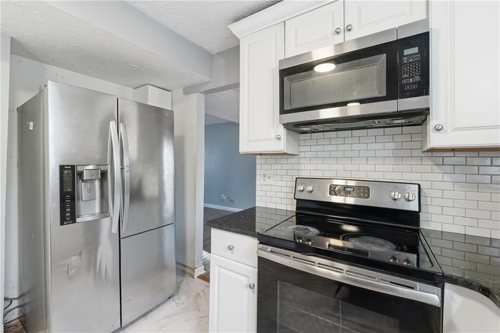 4828 Oak Path Stone Mountain, GA 30088 - Photo 13 of 40 a kitchen with granite countertop a stove and a microwave