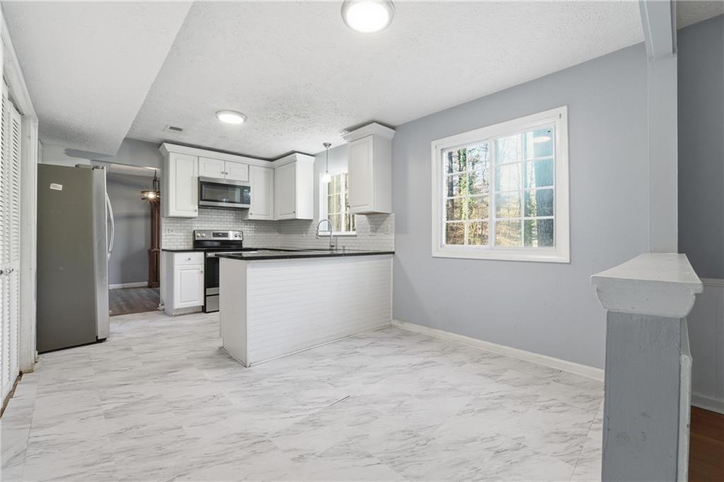 4828 Oak Path Stone Mountain, GA 30088 - Photo 16 of 40 a kitchen with kitchen island a sink stainless steel appliances cabinets and a window
