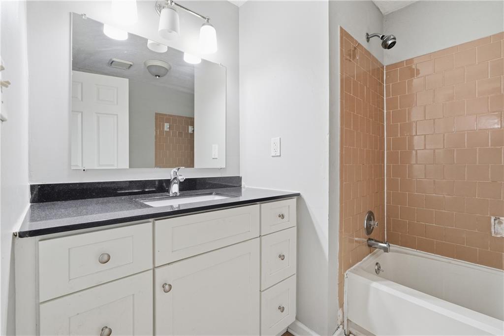 4828 Oak Path Stone Mountain, GA 30088 - Photo 21 of 40 a bathroom with a sink vanity granite tub shower and a mirror