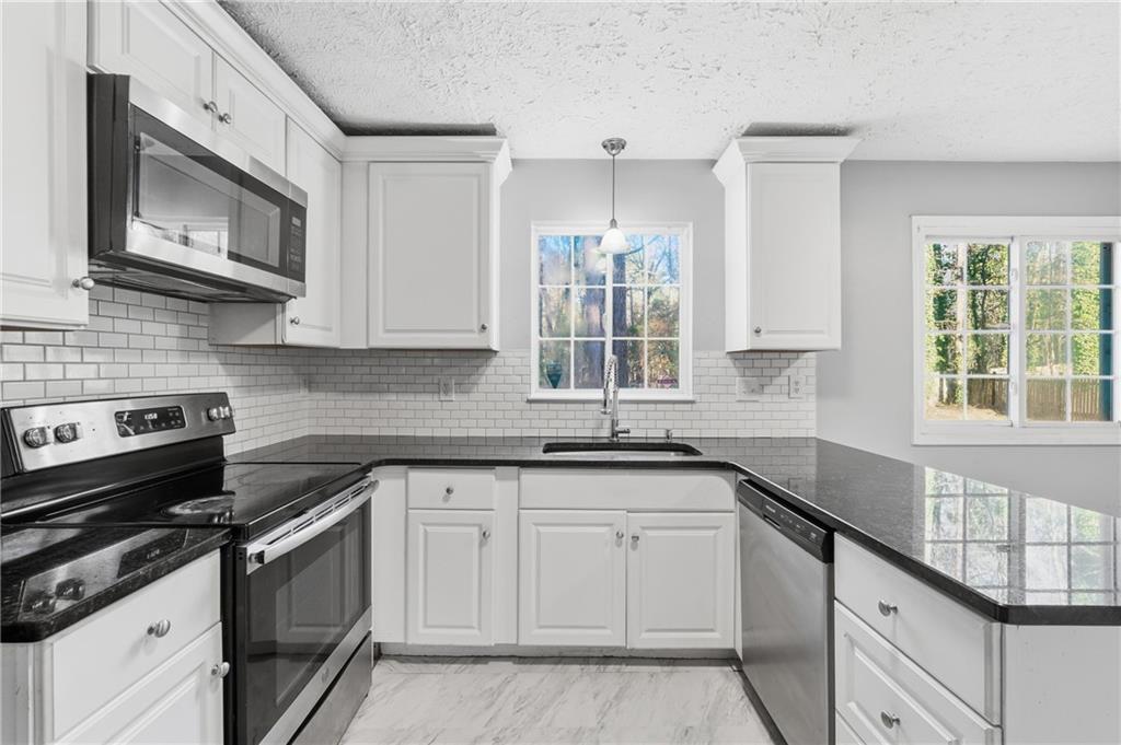 4828 Oak Path Stone Mountain, GA 30088 - Photo 10 of 40 a kitchen with granite countertop white cabinets stainless steel appliances a sink and a window