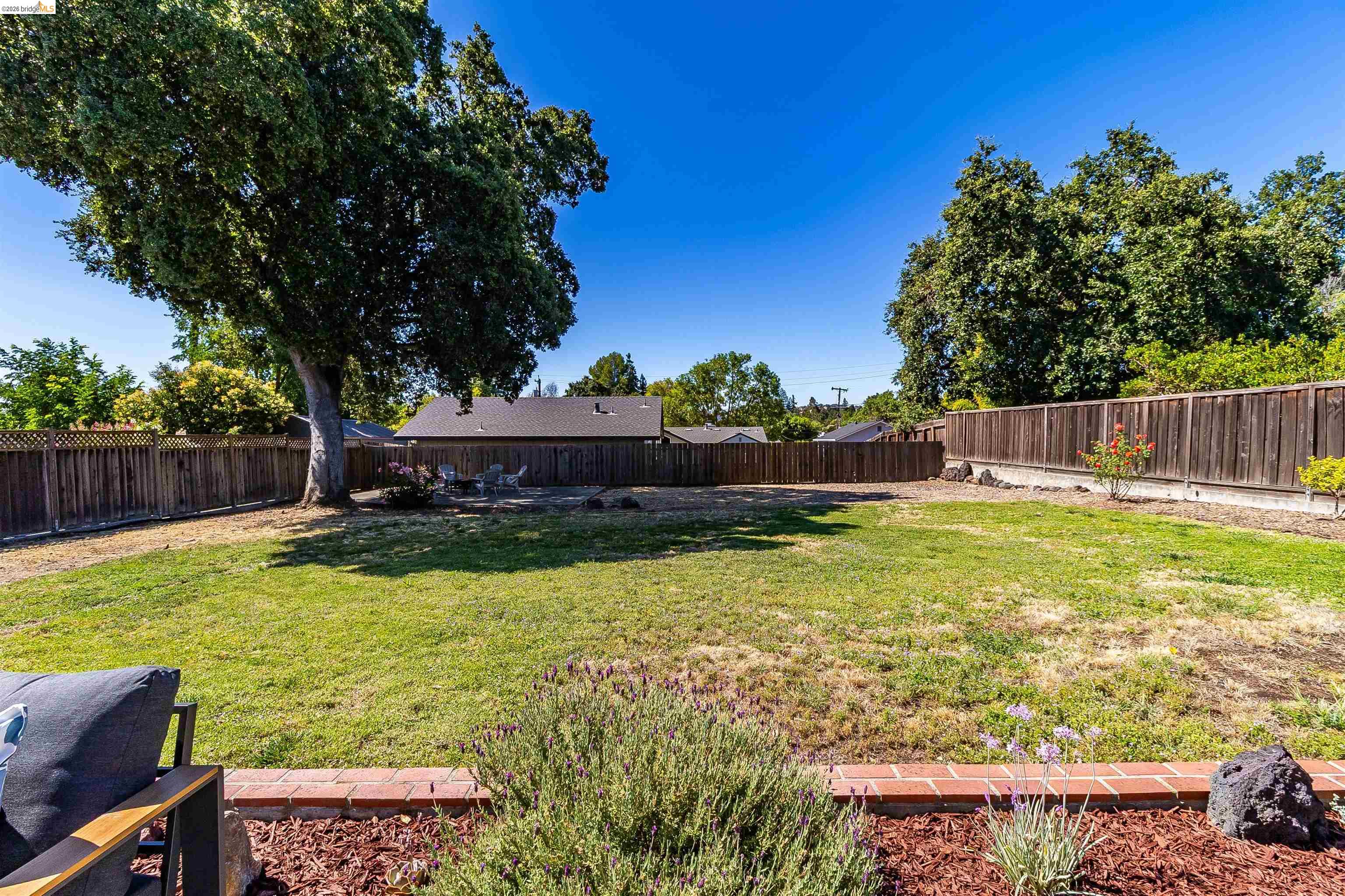 346 Valley View Road Pleasant Hill, CA 94523 - Photo 40 of 57 Expansive backyard featuring a mature tree, perimeter wood fencing, and a brick-edged planting bed