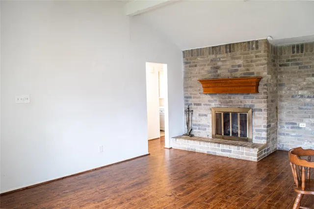 an empty room with wooden floor and a fireplace